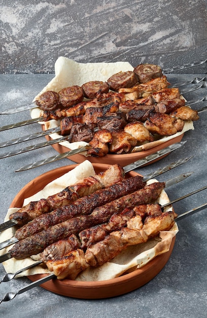 Photo overhead view of assortment of shashlik and kebabs over grey background