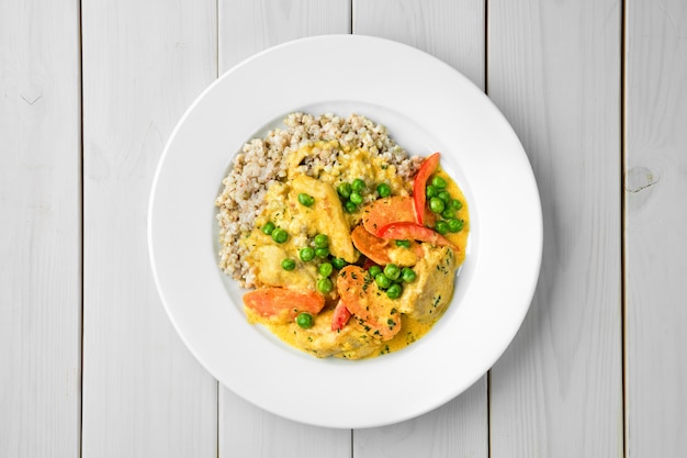 Overhead view of beef stew with carrot, peas and bell pepper served with green buckwheat