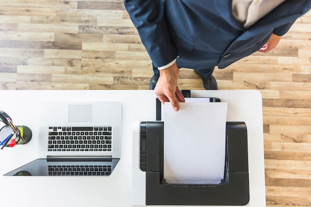 An overhead view of businessman taking paper from printer in the office