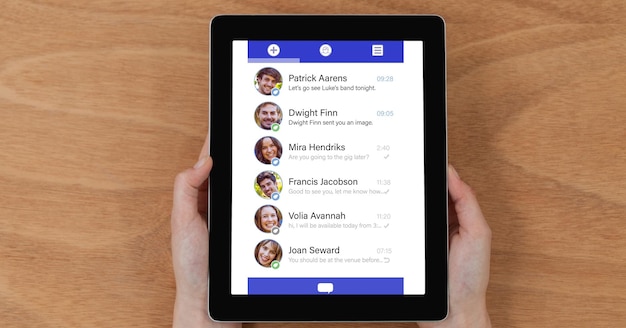 Overhead view of chat list on tablet computer held by person at table