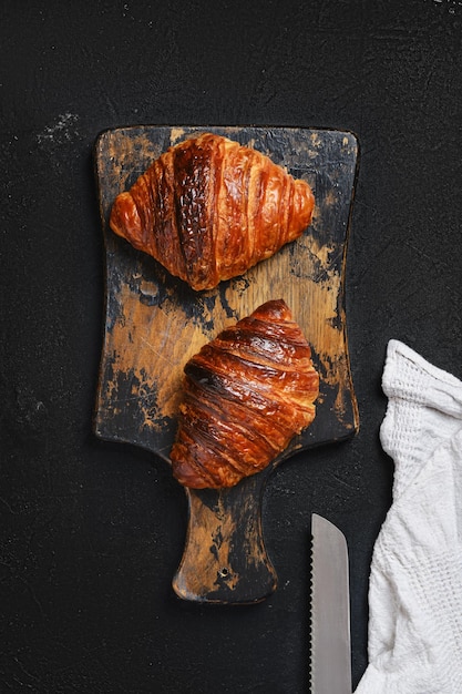 Overhead view of crispy croissant on wooden serving board