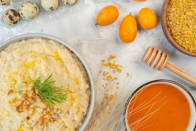 Overhead view of delicious breakfast with oats eggs brown rice spikes honey on ice background