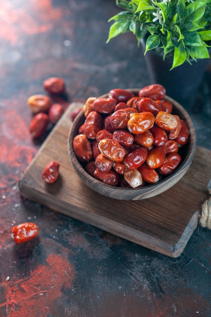 Overhead view of fresh raw silverberry fruits in a bowl on a wooden cutting board and flower pot on mix colors background