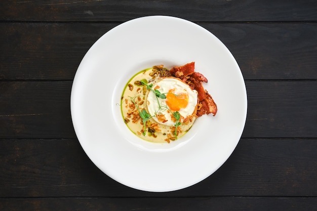 Overhead view of fried egg with bacon slices and chips