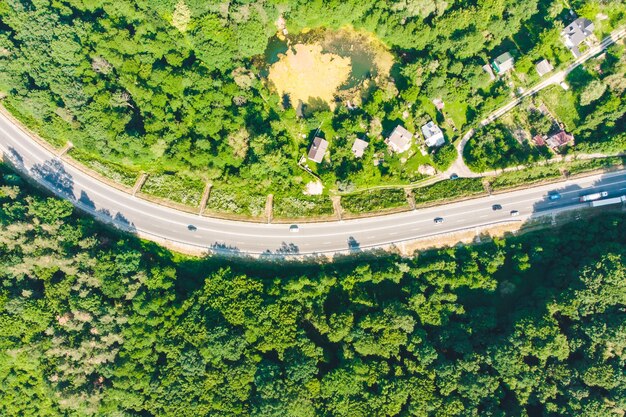 Overhead view of highway near village. forest around