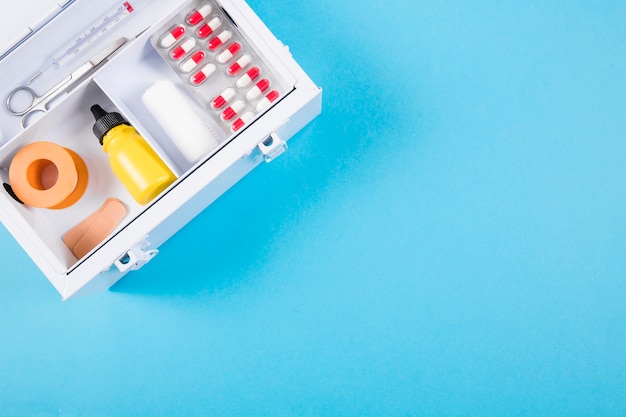 Overhead view of medical first aid kit on blue background