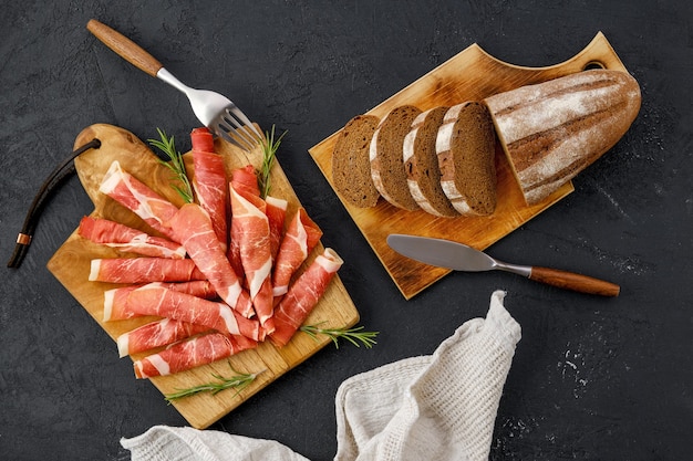 Overhead view of rolled slices of jamon on wooden cutting board