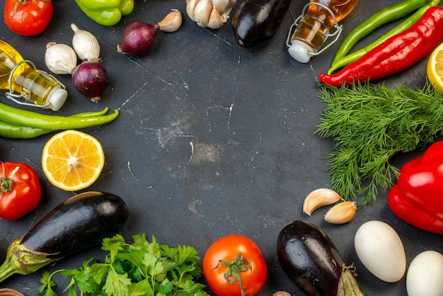 Overhead view of round shaped free space fresh vegetables fallen oil bottle eggs lemons spices on black background