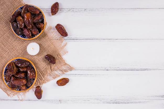 An overhead view of two bowls with ripe juicy dates on white wooded table