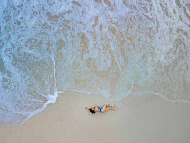 Overhead view of woman in blue swimsuit at sea beach