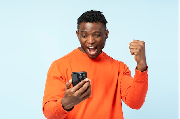 overjoyed African American man holding mobile phone sports betting win money celebration success