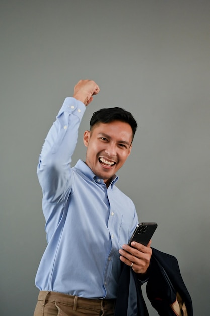 Overjoyed Asian businessman raising his hand rejoicing celebrating his success