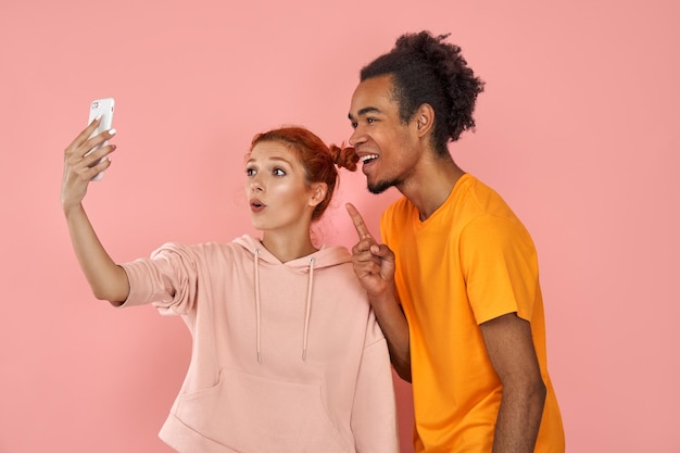 Photo overjoyed dark skinned guy laughs sincerely pose for selfie with ginger girlfriend have fun together