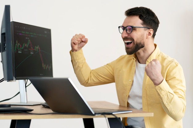 Overjoyed trader celebration success earn money looking at rise of crypto chart sitting in office