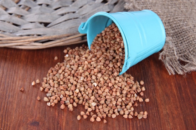 Overturned bucket with grains on wooden background