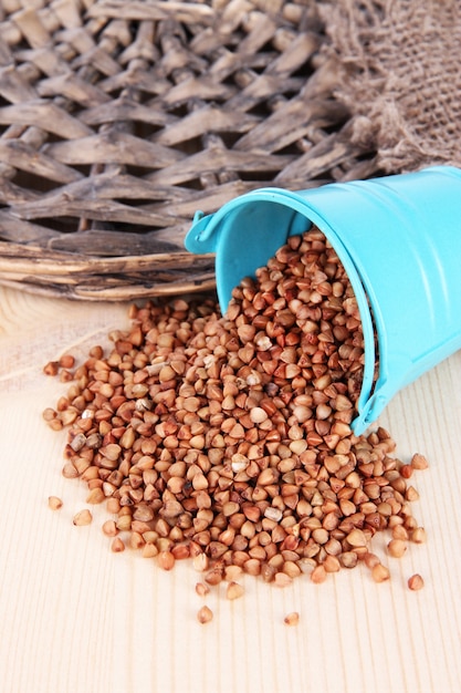 Overturned bucket with grains on wooden background