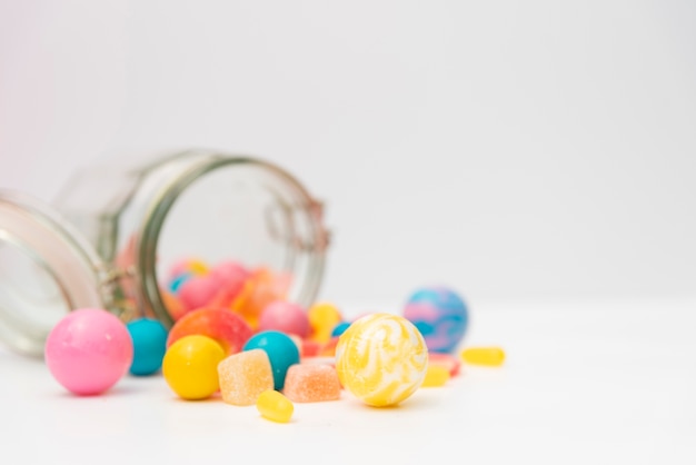 Overturned jar with delicious candies on table