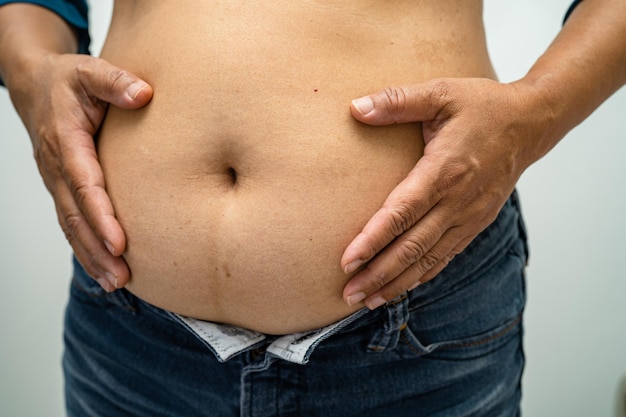 Overweight Asian woman show fat belly at office