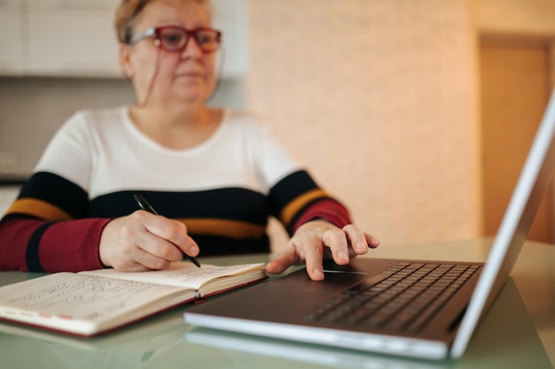 An overweight elderly woman sits at her desk and studies through eeducation on her laptop