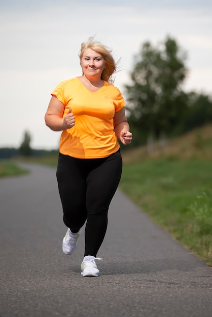 Overweight European middleaged woman in tracksuit jogging playing sports