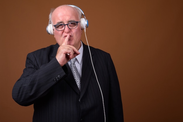 Overweight senior businessman listening music with headphones