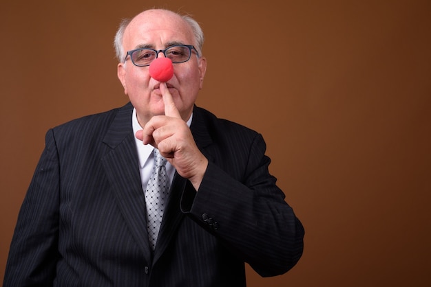 Overweight senior businessman wearing red clown nose