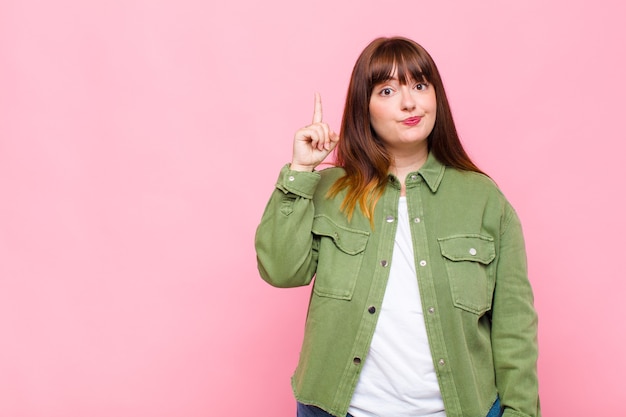 Overweight woman feeling like a genius holding finger proudly up in the air after realizing a great idea, saying eureka