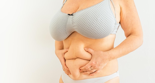 overweight woman holding fold of excess fat on belly, body positivity