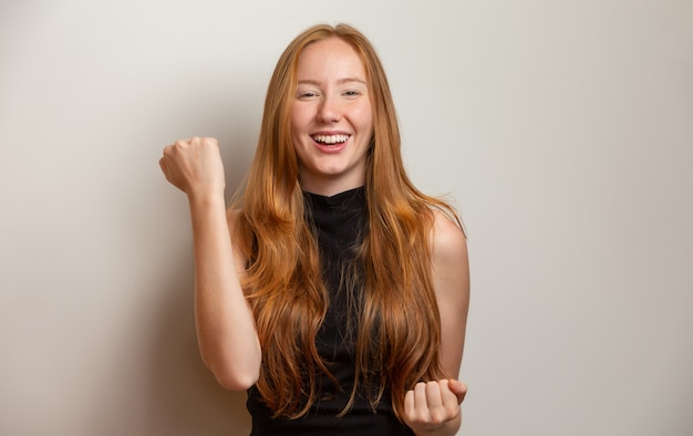 Overwhelmed excited smiling, happy redhead girl celebrating amazing news, achieve victory, winning competition, triumphing as become champion, gain goal or unexpected lucky event happened. On white.