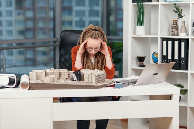 Overworked business woman feeling stress about some problems with architectural and design project of future building.