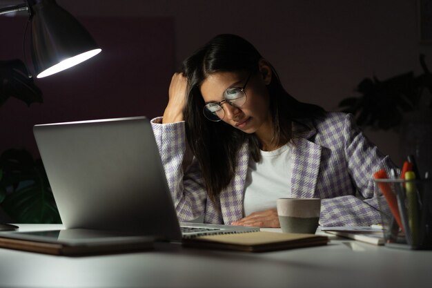 Overworked Indian mixed-race businesswoman suffering from headache and thinking how to end work late evening