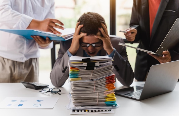 Overworked sad businessman with stack of papers business people deadline stress and paperwork concept