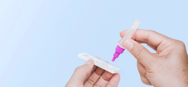 Own hand placing the secretions sample into the SARS CoV-2 Rapid antigen test kit (ATK) with the extraction tube,copy space,Coronavirus infectious protective concept