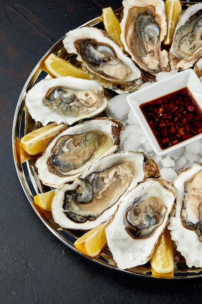 Oysters with lemon served on black round platter Luxury delicatessen seafood