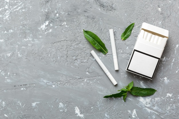 Pack of menthol cigarettes and fresh mint on colored table Menthol cigarettes top view flat lay