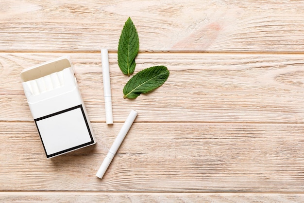 Pack of menthol cigarettes and fresh mint on colored table Menthol cigarettes top view flat lay