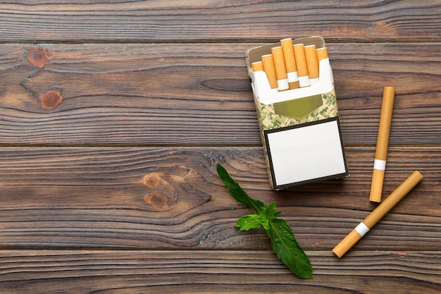 Pack of menthol cigarettes and fresh mint on colored table Menthol cigarettes top view flat lay