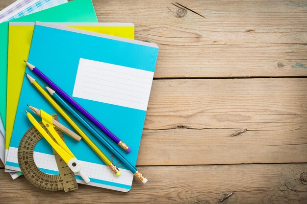 A pack of notebooks for school lies on the old wooden table