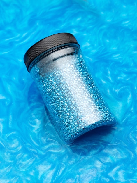 A package of blue glitter crystal salt for relaxation in the bath Jar of shimmering blue sea salt in colored water The idea of home treatment aromatherapy and self care Cosmetics beauty care