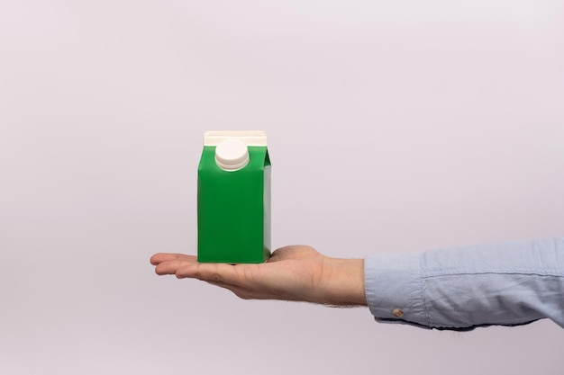 Packaging cartboard pack Green cardboard container with lid for milk or juice on mens hand mock up