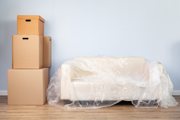 Photo packed household stuff in boxes and packed sofa for moving