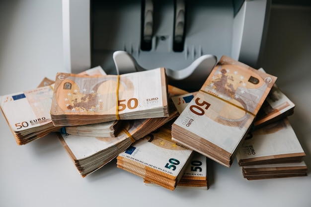 Packs of 50 euro bills next to a counting machine