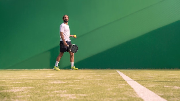 Padel player with black racket playing a match in the open behind the net court