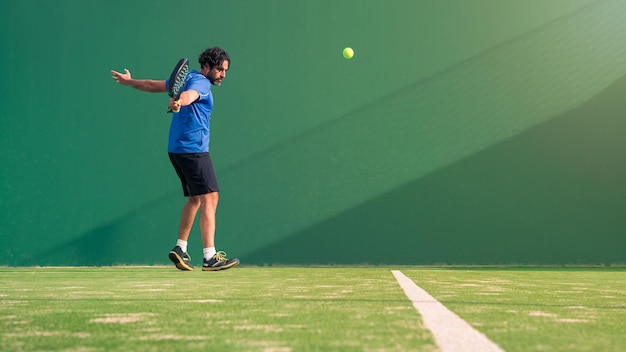 Padel player with black racket playing a match in the open behind the net court