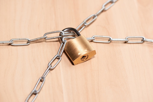 Padlock and chain on wooden table. Concept protection.