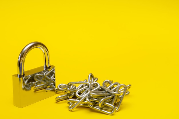 Padlock with chain on yellow background with copy space