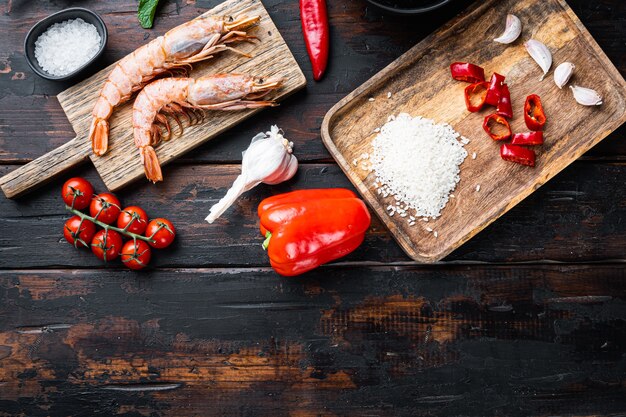 Paella, seafood ingredients on old wooden dark table, top view with space for text