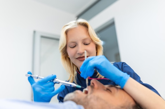 Painkiller anesthesia injection Dentist examining a patient's teeth in modern dentistry office Closeup cropped picture with copyspace Female Doctor in blue uniform