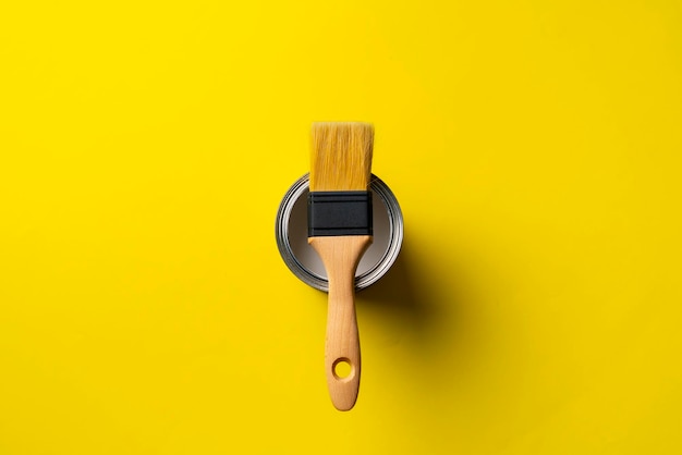 A paint brush on top of can with paint on the colored surface creative art concept