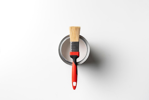 A paint brush on top of can with paint on the colored surface creative art concept